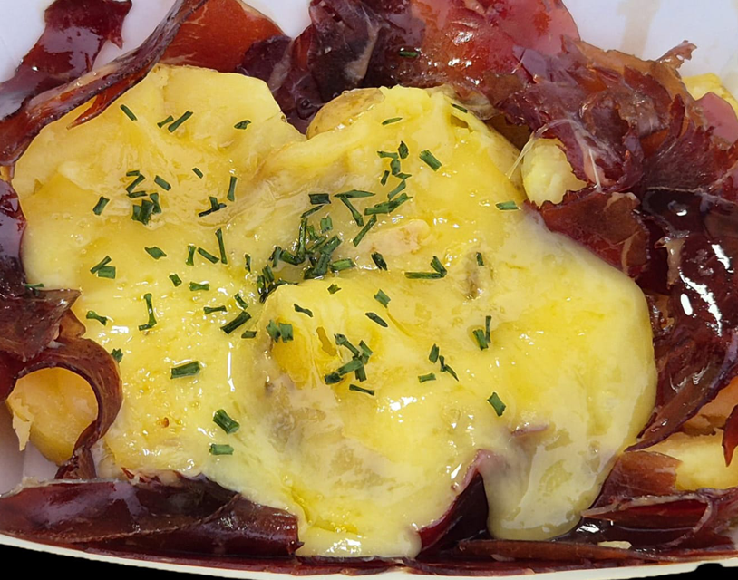 plato de patata con queso raclette fundido y cecina ahumada