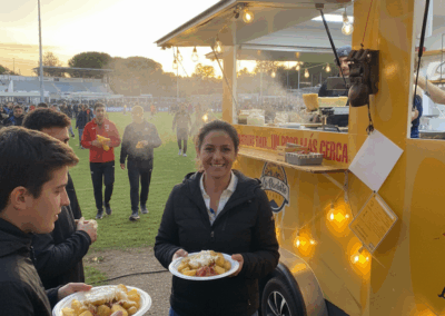 Mujer disfrutando de su plato de Raclette frente al foodtruck al atardecer.