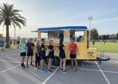 Grupo de deportistas frente al Raclette Foodtruck en evento deportivo.